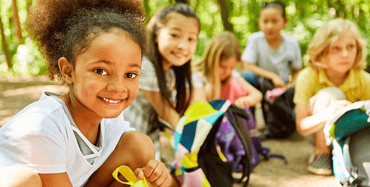 school children smile while on a field trip in the woods