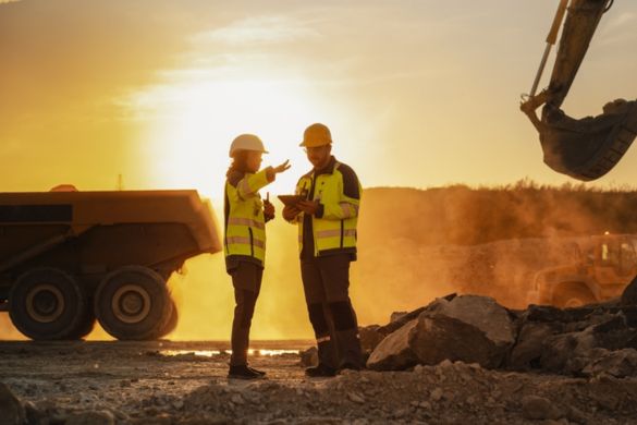 two construction workers looking over a project plan while on a busy worksite